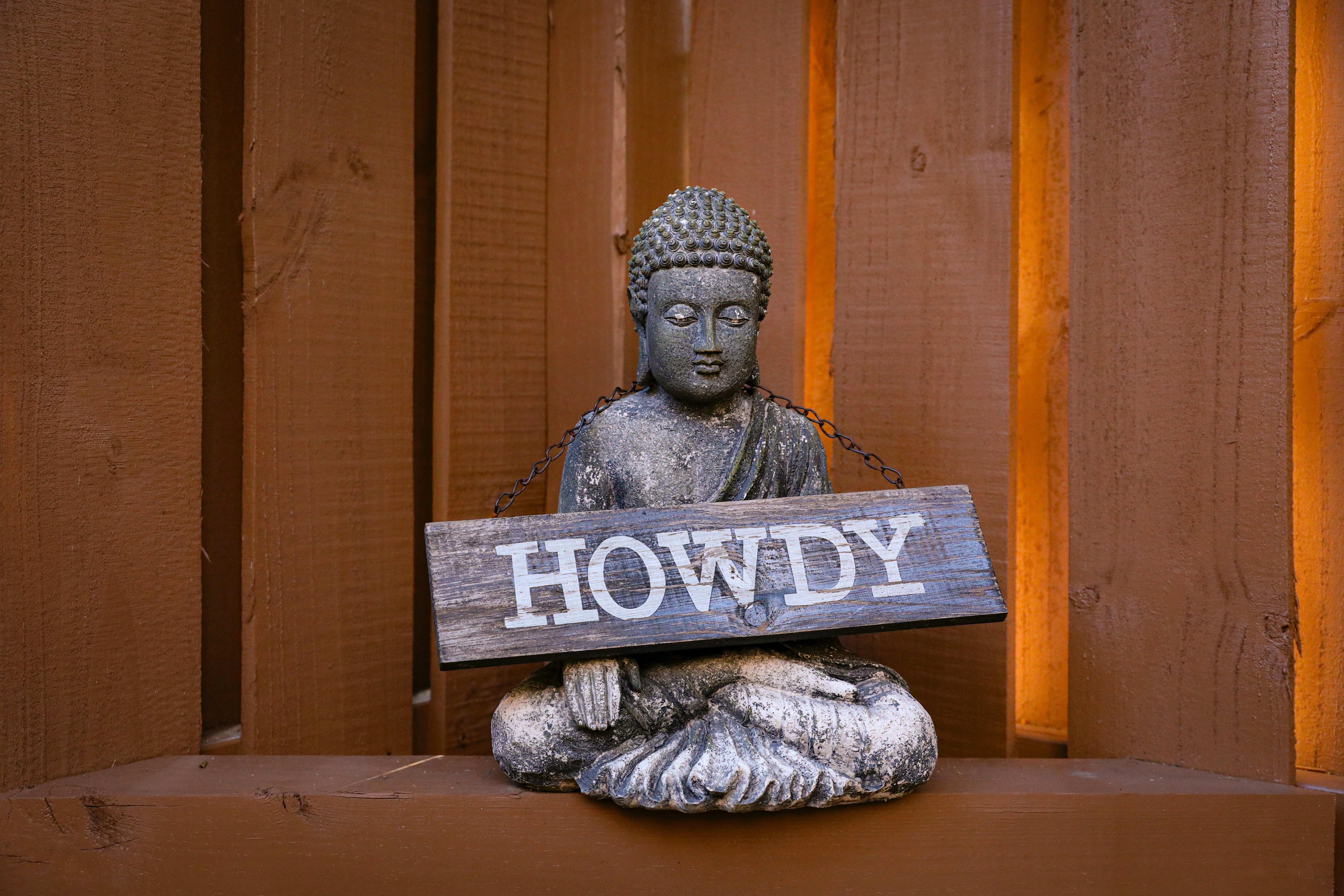 Photograph of meditating figure with sign that reads Howdy by Mick Haupt via Unsplash